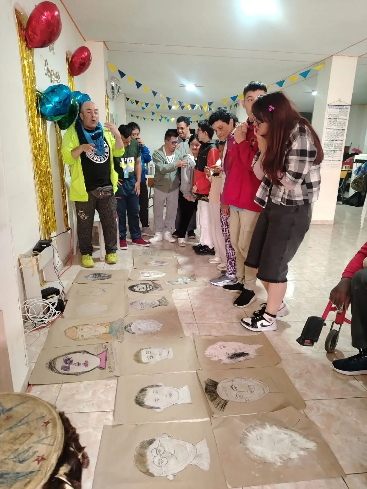 Jóvenes observando sus dibujos extendidos en el piso del salón