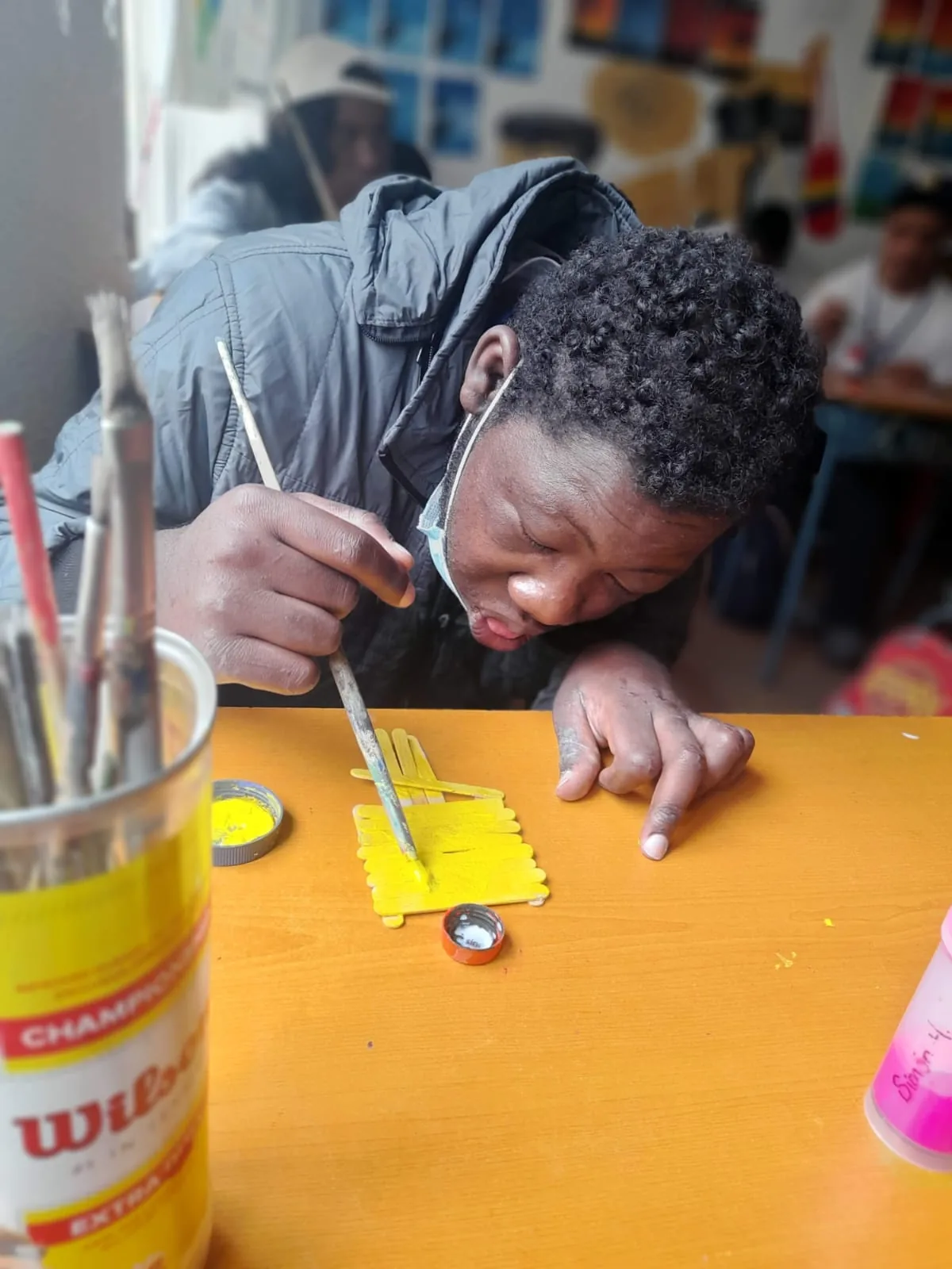 Joven concentrado pintando con pincel sobre una pieza amarilla