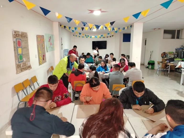 Estudiantes dibujando en grupo en un salón decorado con banderines