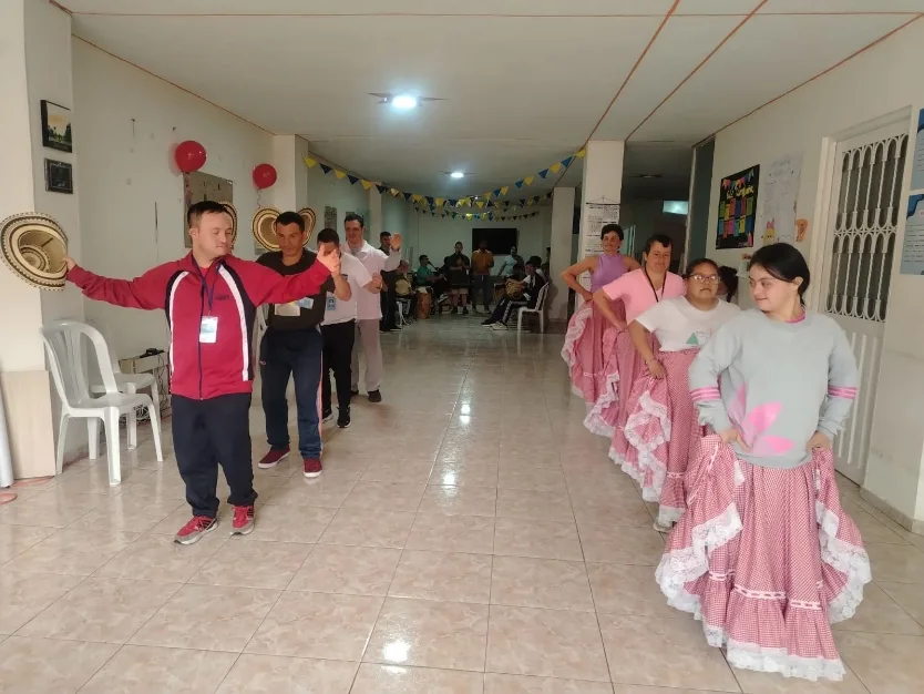 Jóvenes con polleras rosadas ensayando una coreografía en el pasillo de la sede