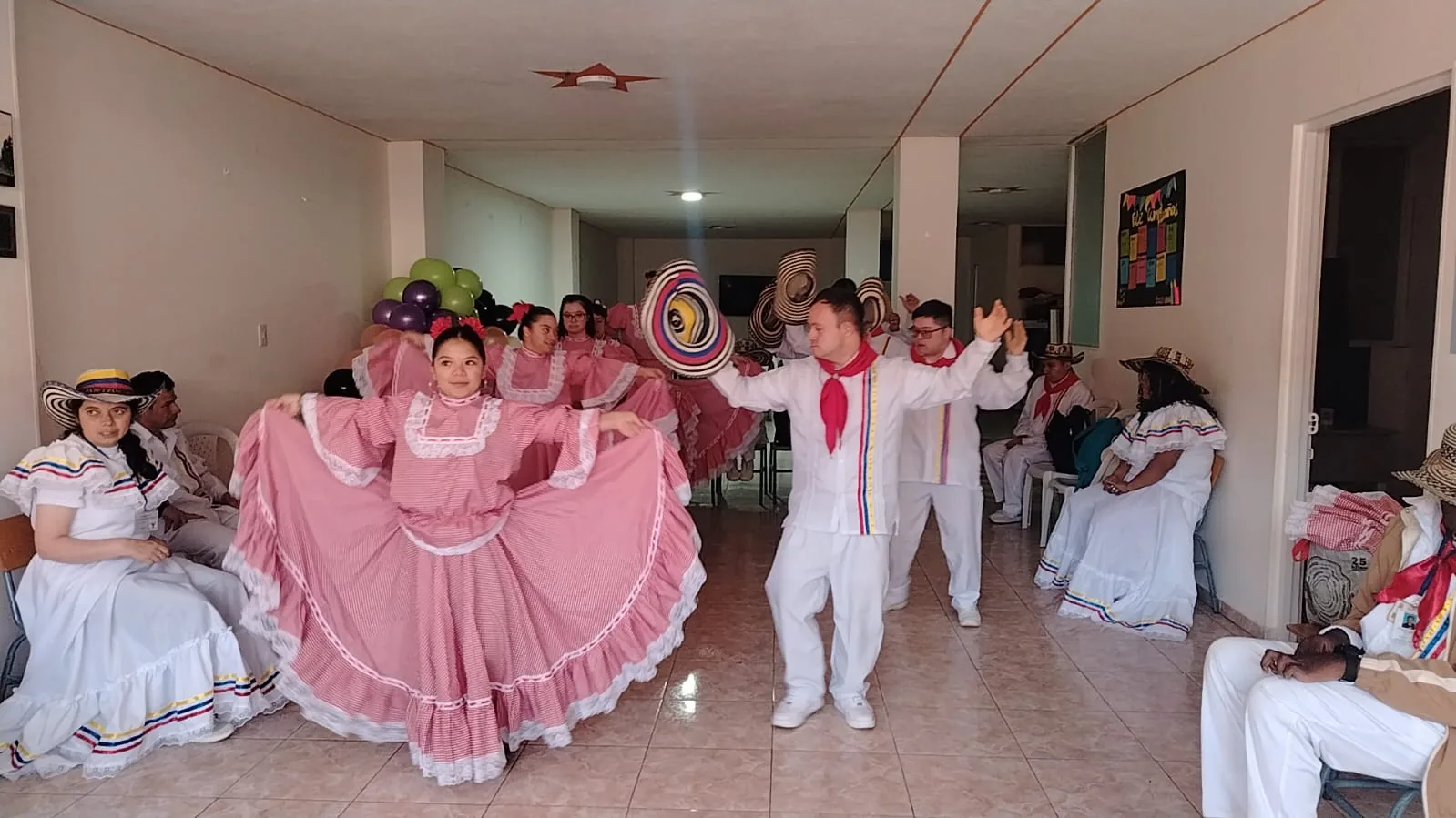 Jóvenes bailando con polleras rosadas y sombreros durante un ensayo