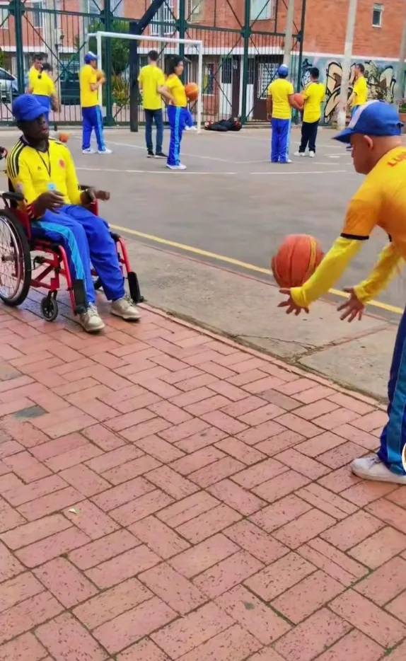 Joven en silla de ruedas y su compañero jugando baloncesto en una cancha
