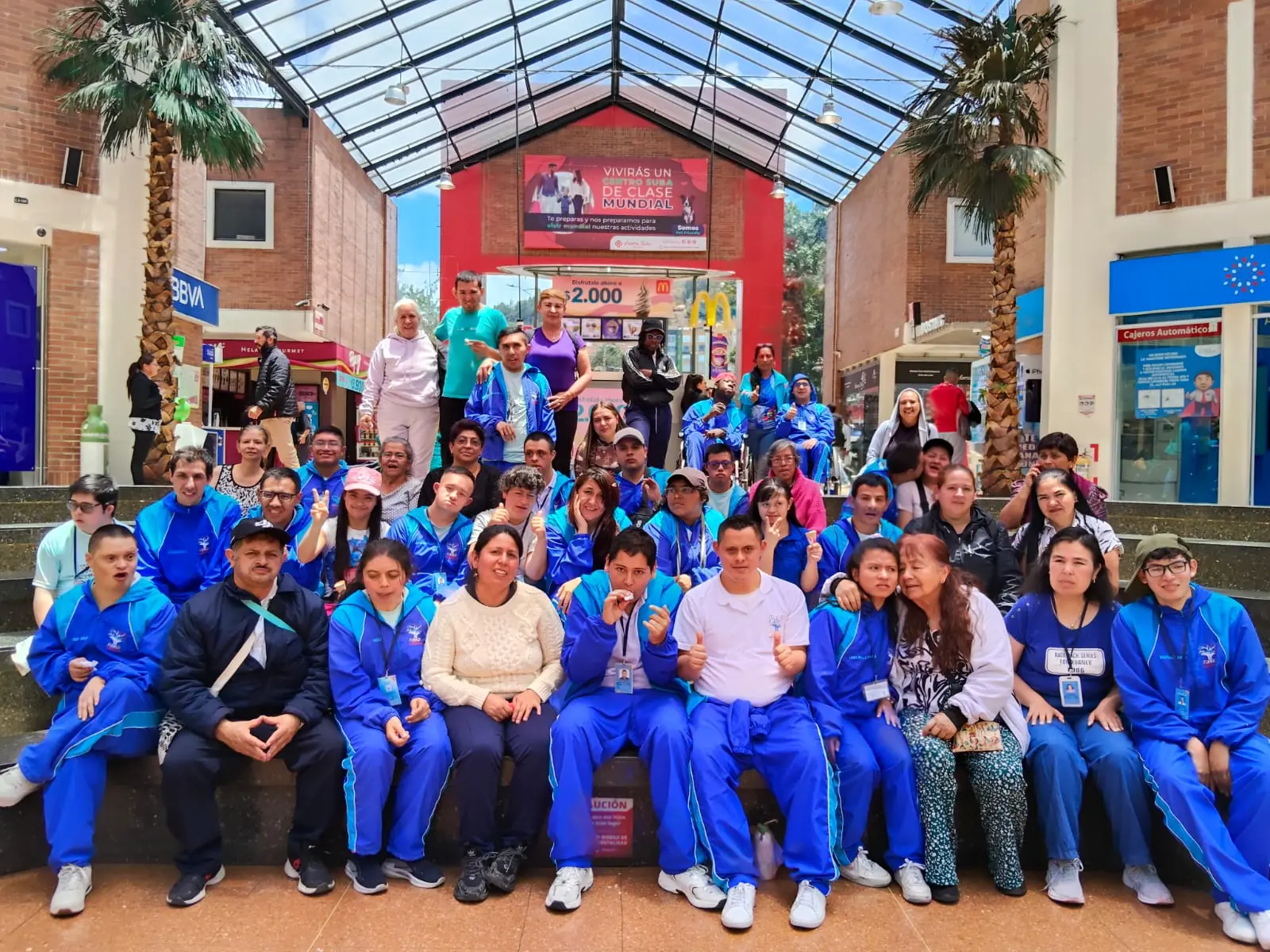 Estudiantes con la sudadera azul de la fundación sentados juntos y sonriendo en una plaza
