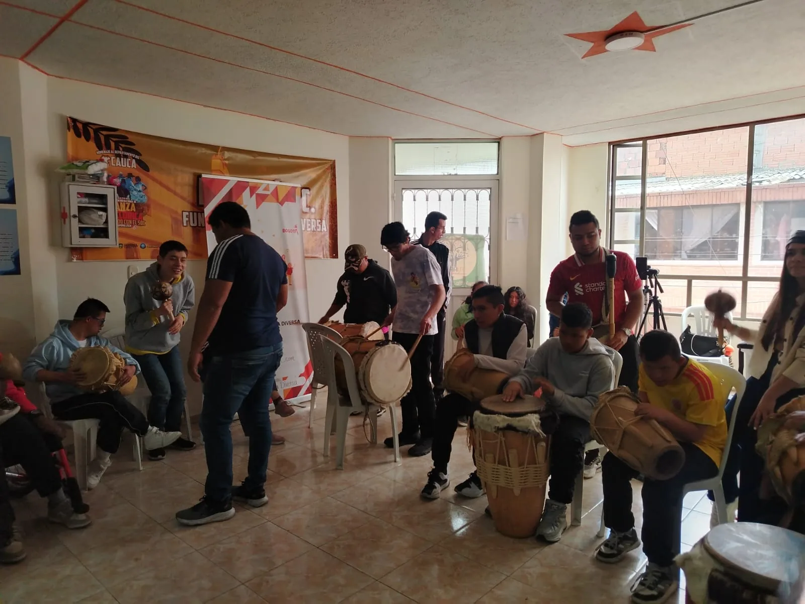 Jóvenes y su profesor tocando tambores durante un ensayo en la sede