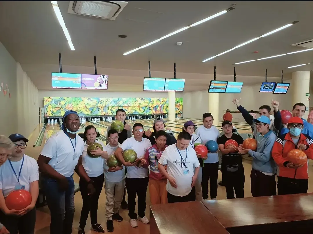 Estudiantes sosteniendo bolas de bolos y celebrando en una pista de bolos