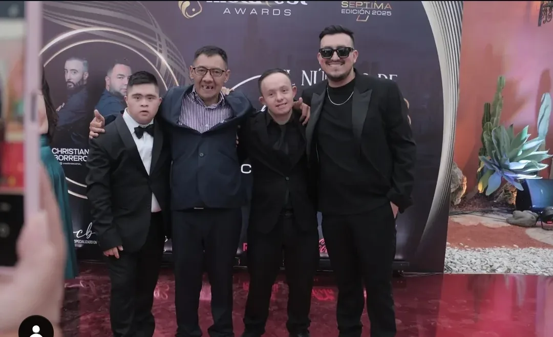 Cuatro asistentes con traje oscuro posando en la alfombra roja de una gala