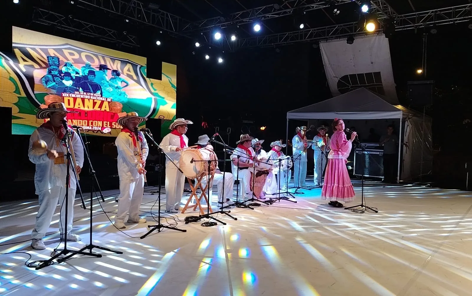 Grupo de música y baile en un escenario iluminado durante el Encuentro «Danzando con el Sol»